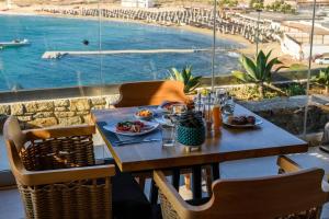 een houten tafel met eten en uitzicht op een zwembad bij Panormos Village Hotel in Panormos Mykonos