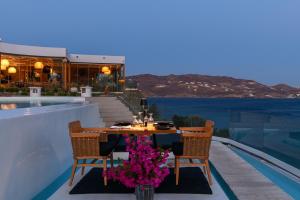 a dining table with chairs and flowers on a balcony at Panormos Village Hotel in Mykonos