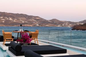 a patio with a table and chairs next to the water at Panormos Village Hotel in Mykonos