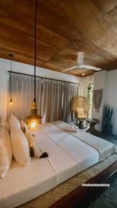 1 dormitorio con 1 cama blanca grande y techo de madera en Kaha Island Stay, en Santa Monica