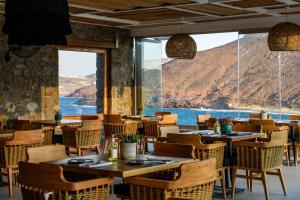 a restaurant with tables and chairs and a large window at Panormos Village Hotel in Mykonos