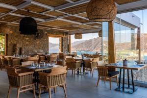 a restaurant with tables and chairs and large windows at Panormos Village Seaside Resort in Mykonos