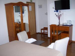 een kamer met een tafel en stoelen en een televisie bij Hotel Santa Apolonia in Bragança