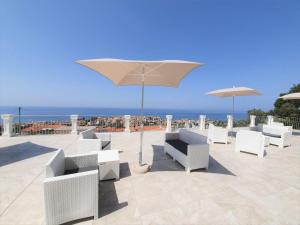 a patio with white chairs and an umbrella at Appartamenti Borgo Panoramico N 9 in Tropea