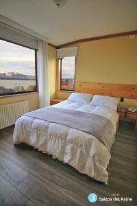 1 cama grande en un dormitorio con 2 ventanas en Hotel Saltos del Paine, en Puerto Natales