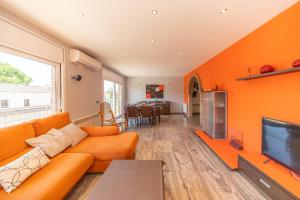 ein orangefarbenes Wohnzimmer mit einem Sofa und einem TV in der Unterkunft Villa Eugenia in L'Escala