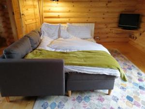 a bed in a room with a couch and a television at Ravenglass Log Cabin in Ravenglass