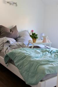 ein Bett mit einer grünen Bettdecke und einem Tisch in der Unterkunft Kleines Landleben in Hohwacht
