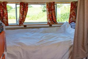 a bed in a room with two windows at Retro Caravan with Mountain Views in Abergavenny
