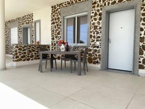 a table and chairs in front of a stone wall at La Perla Mare Apartments in Capo Vaticano