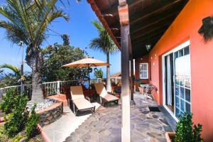 een patio met stoelen en een parasol op een huis bij Casas los Alisios in Los Quemados