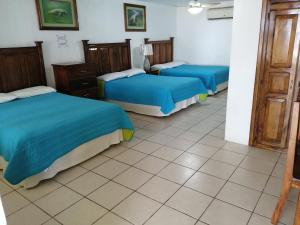 Cette chambre comprend 3 lits avec des draps bleus. dans l'établissement Freedom Shores "La Gringa" Hotel - Universally Designed, à Isla Aguada