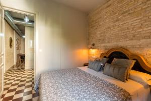 a bedroom with a bed and a brick wall at Doña Elvira Suites Cathedral in Seville