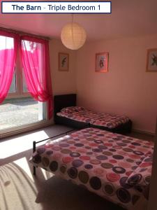 um quarto com 2 camas e uma janela com cortinas cor-de-rosa em The Barn Complex em Argenton lʼÉglise
