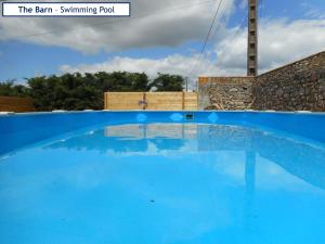 a blue swimming pool with the sun shining on it at The Barn Complex in Argenton lʼÉglise