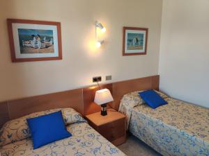 two beds in a hotel room with blue pillows at Mar Blau in Port d'Alcudia