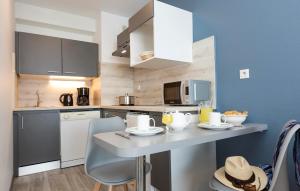 a kitchen with a table with chairs and a counter top at Résidence Odalys Archipel in La Rochelle