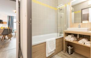 a bathroom with a tub and a sink at Résidence Odalys Archipel in La Rochelle