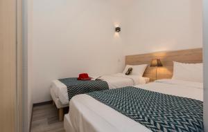a hotel room with two beds and a hat on a table at Résidence Odalys Archipel in La Rochelle