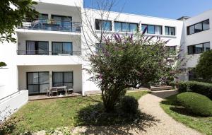 a white building with a tree in front of it at Résidence Odalys Archipel in La Rochelle
