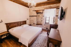 a bedroom with a white bed and a brick wall at Beratino Hotel in Berat