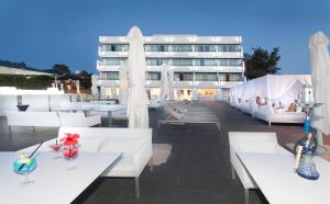 a hotel with white tables and chairs and a building at Marina Playa Hotel Apartments by Typic Hotels - Adults Only in San Antonio Bay