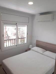 1 dormitorio con 1 cama blanca y 2 ventanas en Apartamentos Dins Mar Apto. 3, en Torredembarra
