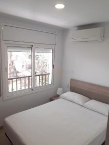 a bedroom with a white bed and two windows at Apartamentos Dins Mar Apto. 3 in Torredembarra