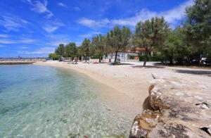 a beach with a group of people sitting on the beach at Apartman Toni in Bibinje