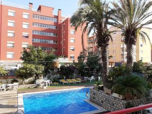 una piscina frente a un edificio con palmeras en Apartaments Mar Blau Calella, en Calella
