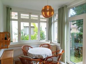 a dining room with a table and chairs and windows at Zöldfa8 in Nagymaros