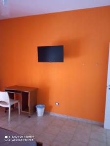 een oranje muur met een bureau en een televisie erop bij Casa peo in Benevento
