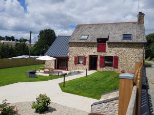 エピニアックにある"La MAISON DE DANA" ENTRE ST MALO & MT ST MICHELの赤い鎧戸と庭のある石造りの家