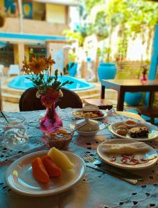 a table with plates of food and a vase of flowers at Pousada Ecos do Mar in Praia do Frances