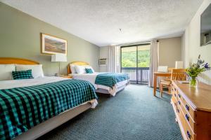 ein Hotelzimmer mit 2 Betten und einem Schreibtisch in der Unterkunft The Inn at Bolton Valley in West Bolton