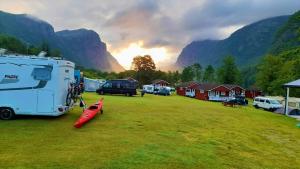 a group of rvs parked in a field with mountains at Wathne Camping in Bjørheimsbygda