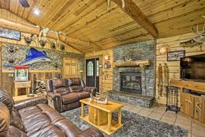 a living room with leather furniture and a stone fireplace at Scenic Cabin on 2 Acres Near Lake Holcombe Marina! in Holcombe