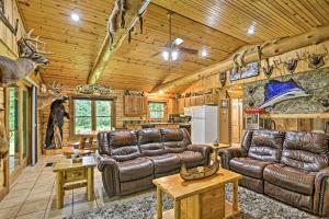 a living room with leather furniture in a log cabin at Scenic Cabin on 2 Acres Near Lake Holcombe Marina! in Holcombe
