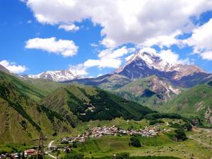 a village in a valley with mountains in the background at Milla in Stepantsminda