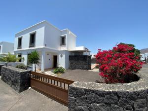 una casa blanca con una valla y flores rojas en Varadero Nauplius, en Playa Blanca