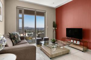 sala de estar con sofá y TV en Easy Stay - The Tyrwhitt Rosebank en Johannesburgo