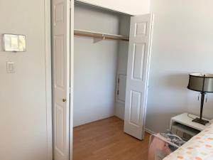 a bedroom with a white closet and a bed at One Bedroom queen bed Sharing Washroom in Tiger Sweet House License## in Richmond