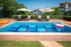 een zwembad met een frisbee en stoelen en een parasol bij Luxury House In Chervenka next to Gradina beach in Chernomorets