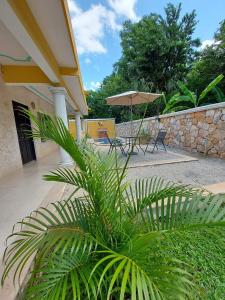 a patio with a table and chairs and an umbrella at Nicol-Haa in Izamal