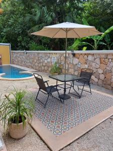 a table and chairs with an umbrella next to a pool at Nicol-Haa in Izamal