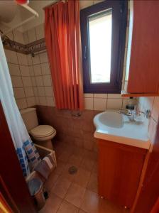 a bathroom with a sink and a toilet and a window at Golden view apartments Myrina Limnos in Mirina
