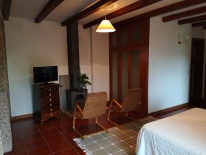 a bedroom with a bed and two chairs and a television at T0 Eira Trás in Vieira do Minho