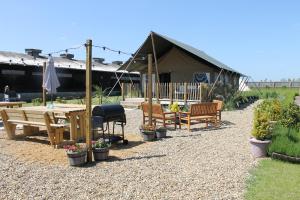 a patio with benches and a table and chairs at Green Rabbit Glamping in Diss