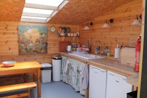 Green Rabbit Glamping في ديس: مطبخ بجدران خشبية وطاولة مع حوض