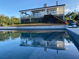 uma casa é refletida em uma piscina de água em Casa das Hortências by Azoresrent em Farroupo